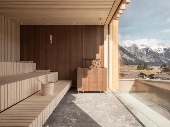 Modern wooden sauna interior with panoramic mountain view through large glass window